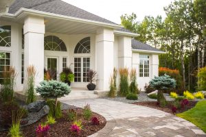 Front yard landscaping in front of a white house with multiple plants