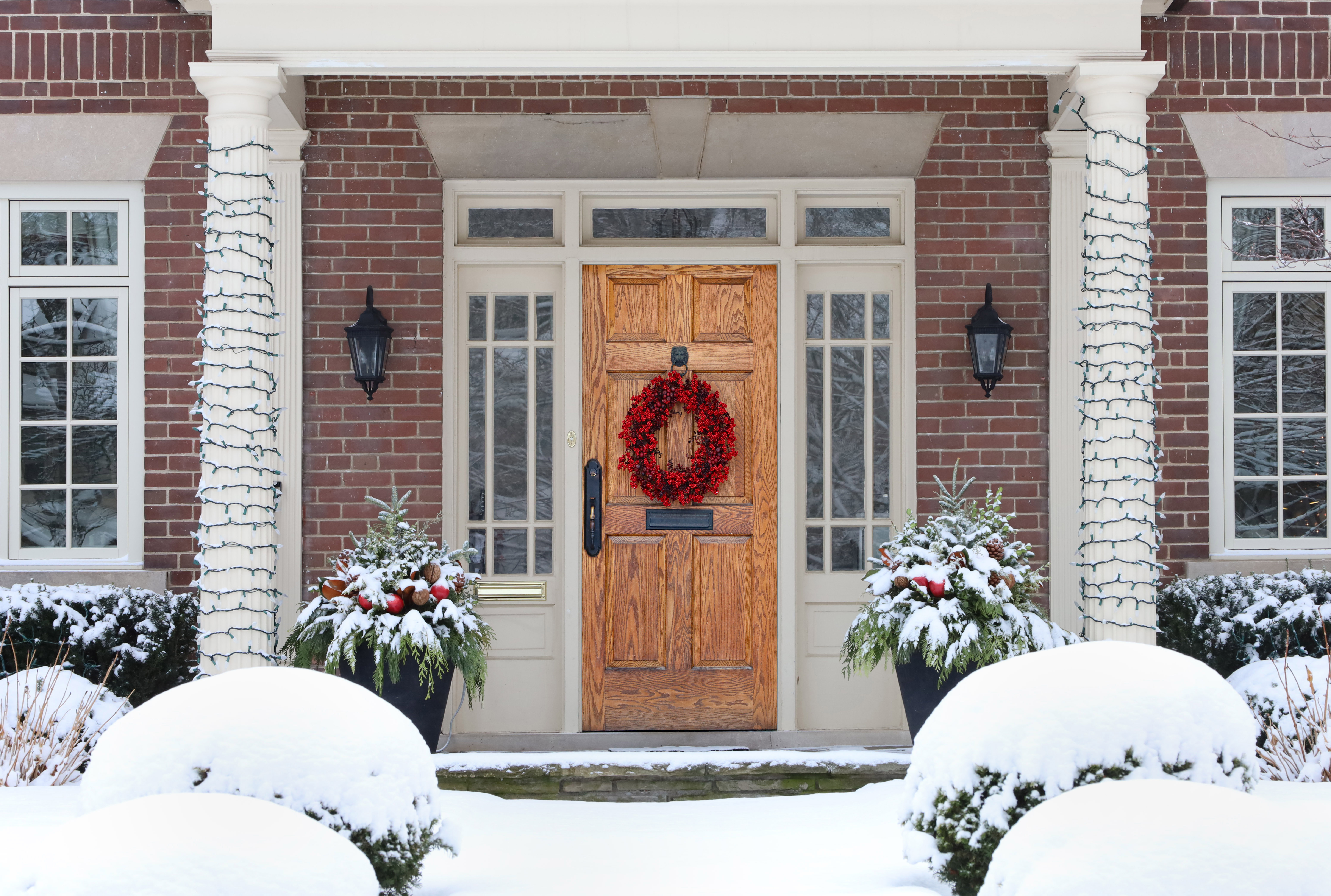 wood grain front door of house with colorful Christmas wreath wi